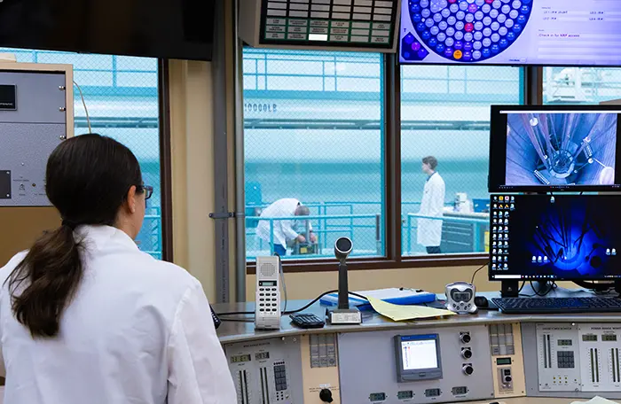 A person in a white lab coat looks at a radiation facility.