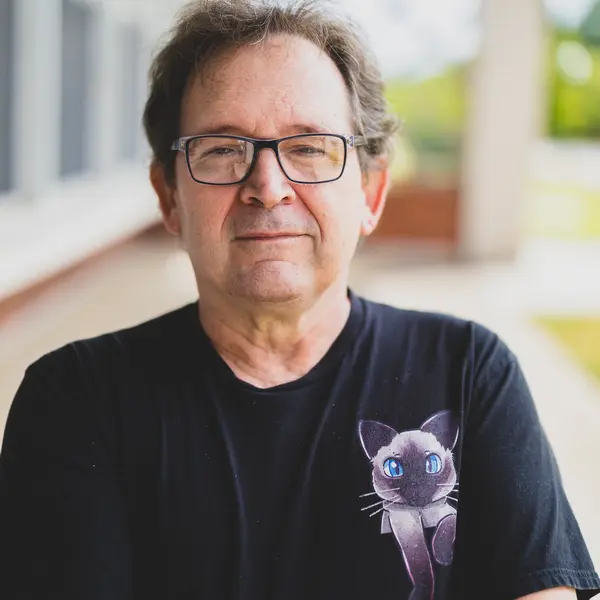 A person wearing a dark colored shirt smiles at the camera. 